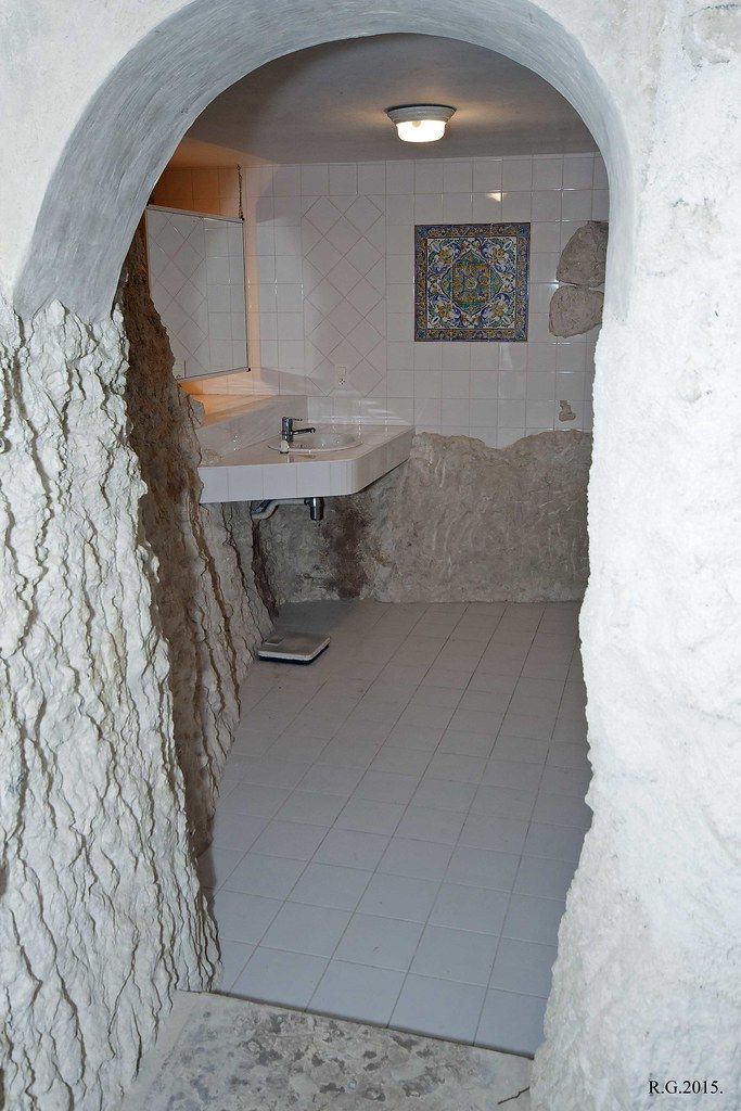 Small white arched bathroom with sink, tiled floor, and a window at the back.