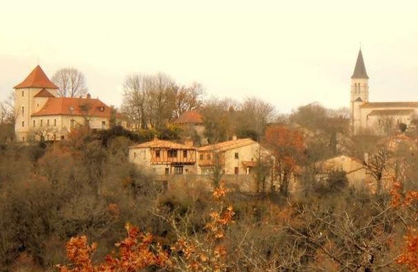 Hilltop village with a church and red-roofed buildings among autumn trees