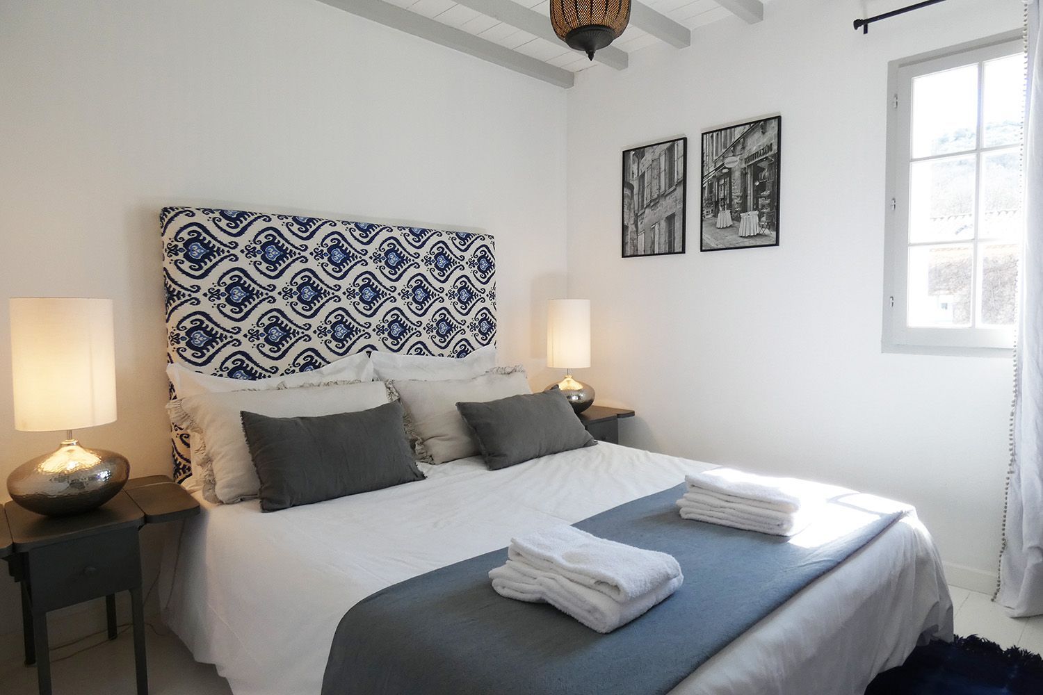 A bedroom with a bed , two lamps and a window at the Mas, Fleur de Lys Retreats