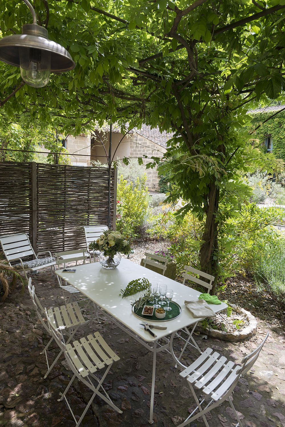 A table and chairs are sitting under a tree in a garden at the Mas, Fleur de Lys Retreats.