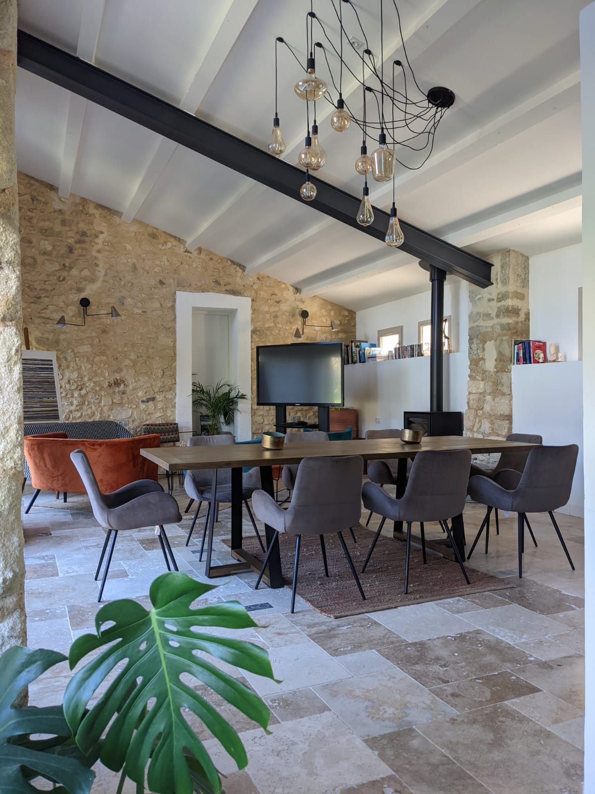 A dining room with a table and chairs and a chandelier hanging from the ceiling  at the Mas, Fleur de Lys Retreats.
