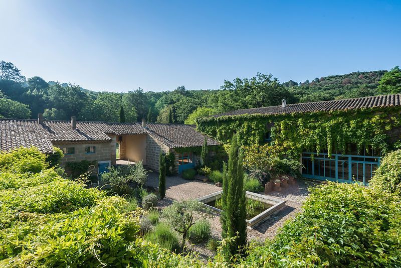 A large house surrounded by trees and bushes in the middle of a forest. Fleur de Lys Retreats at the Mas.