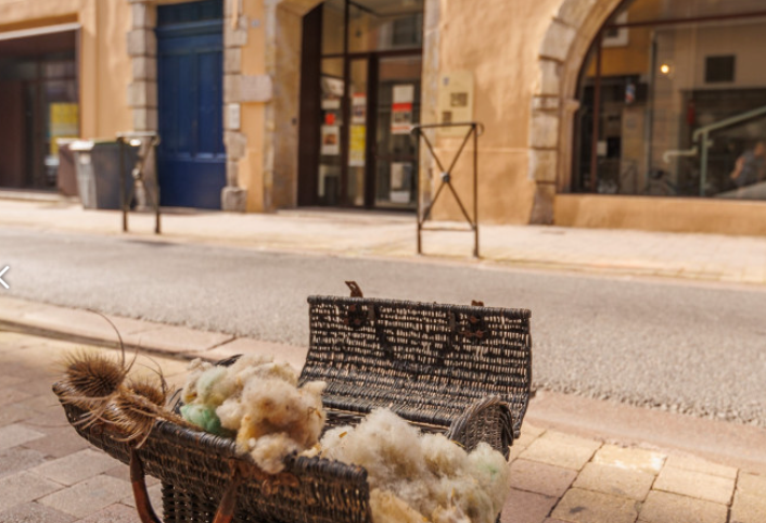 A wicker basket filled with wool sits on the side of a street, in Carcassonne, Fleur de Lys Retreats.