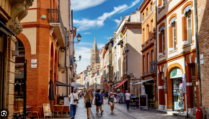 A group of people are walking down a narrow street in Toulouse, Fiver Arts retreat, Fleur de Lys Retreats.