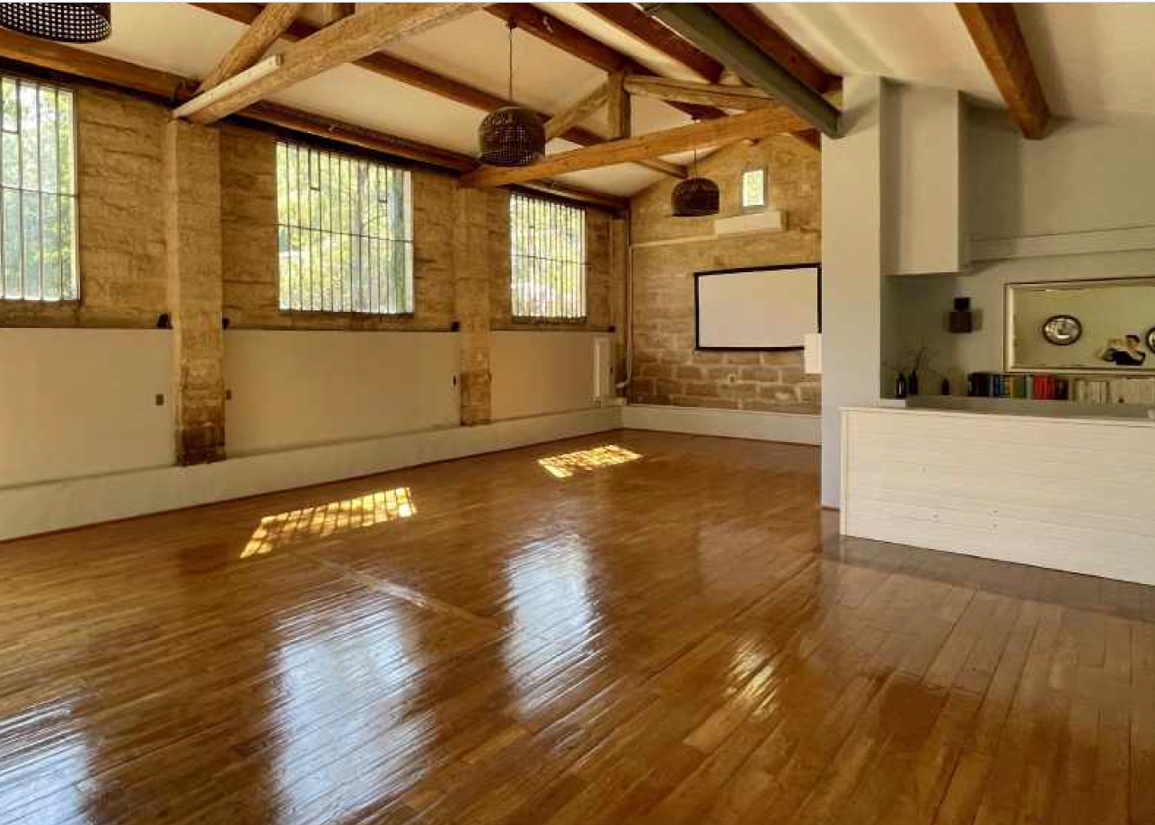 Spacious, light-filled studio with wood floors and stone walls, used for art workshops and mindful movement sessions
