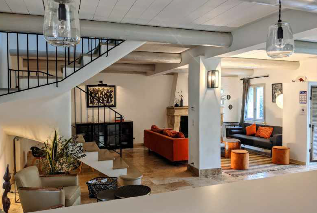 A living room with a couch , chairs , stairs and a fireplace.