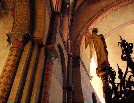 Gothic church interior with arched columns and a statue lit by warm light