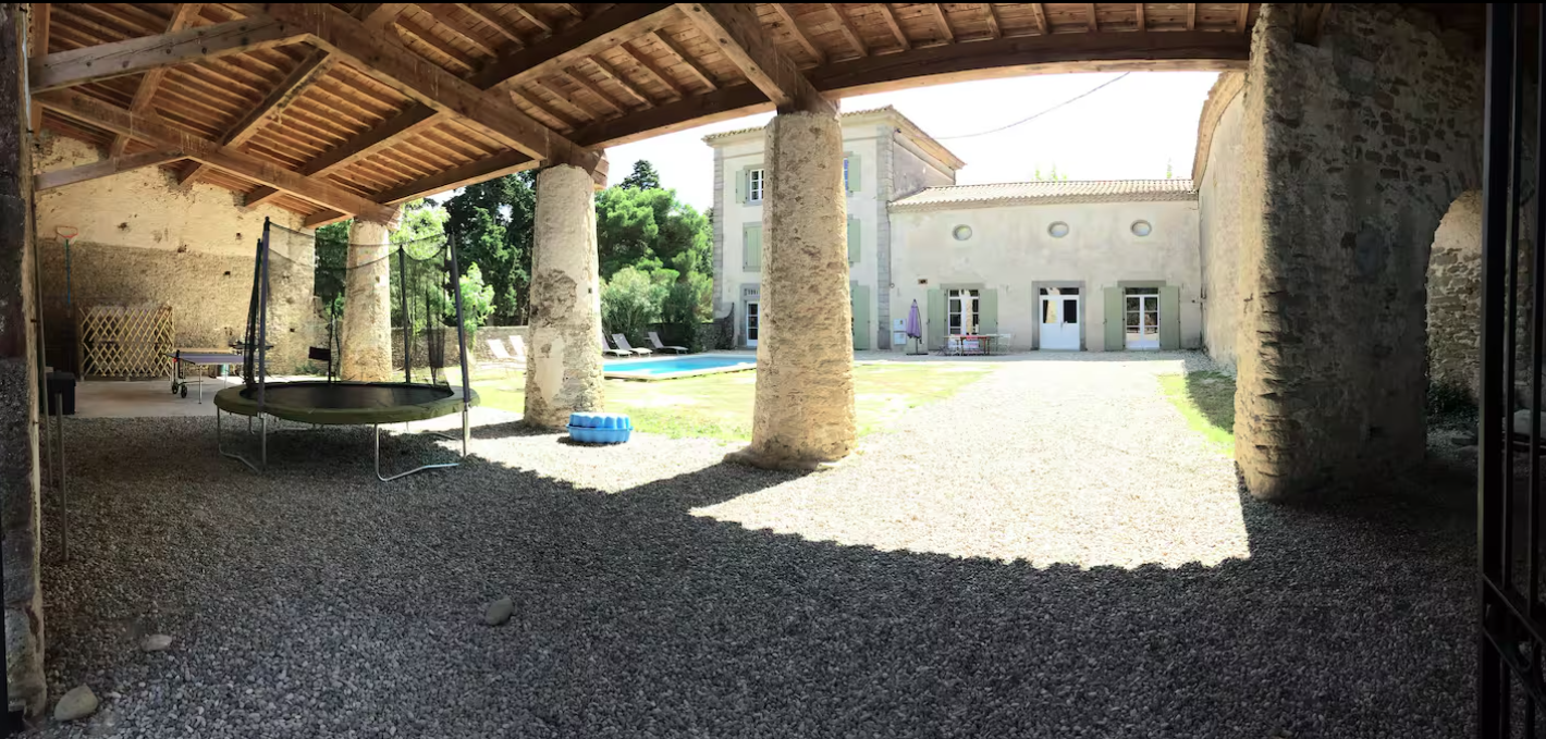 A trampoline is sitting under a covered area in front of a building.