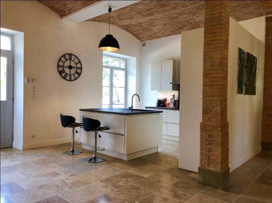 A kitchen with a large island and a clock on the wall.