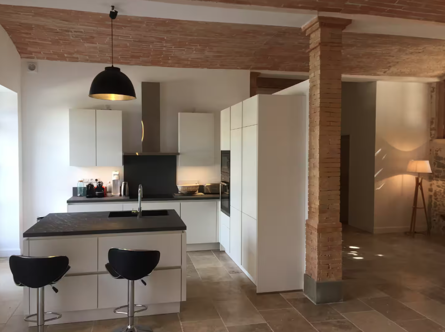 A kitchen with white cabinets and black stools