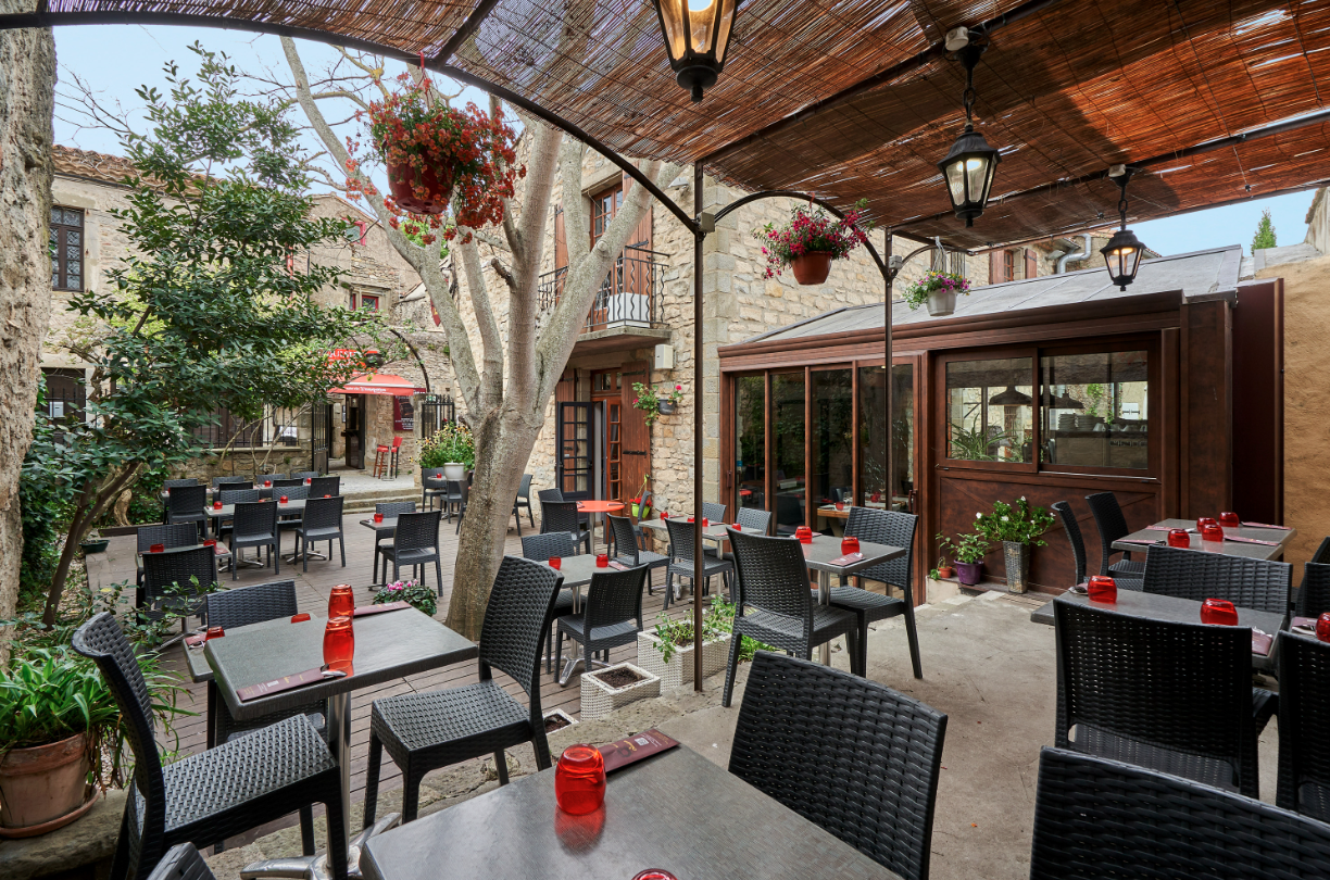 A restaurant patio with tables and chairs under a canopy.