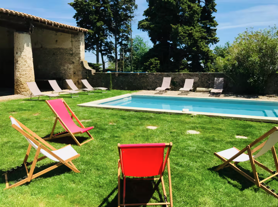 Lawn chairs are lined up in front of a swimming pool.