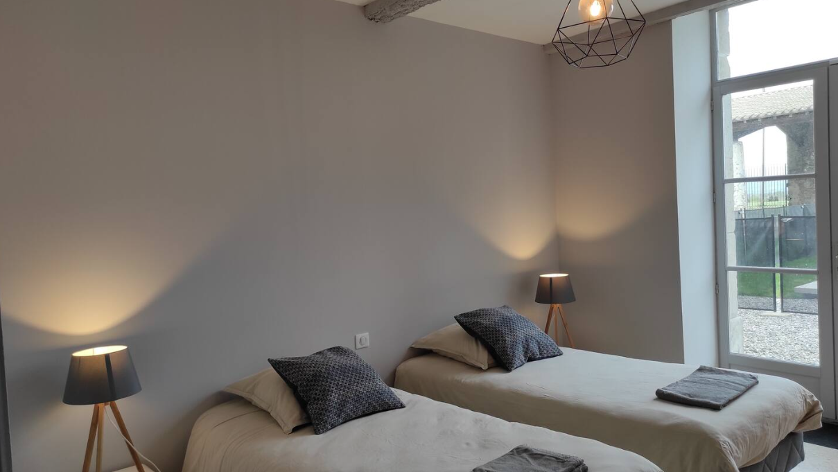 A bedroom with two beds , two lamps and a large window.