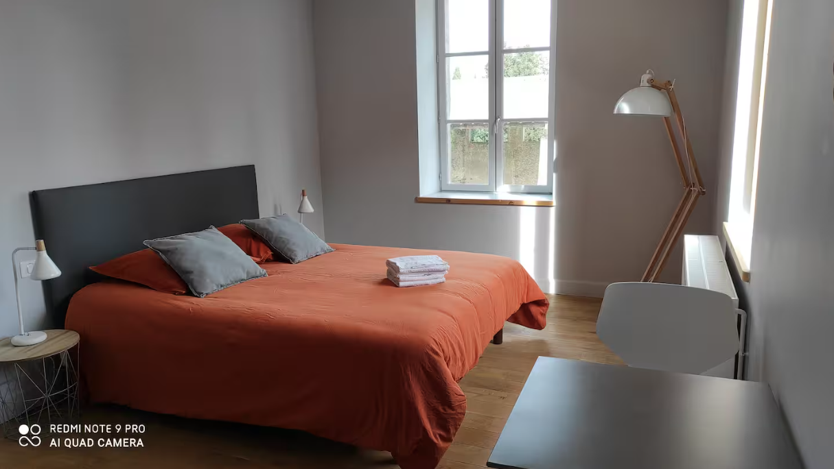 A bedroom with a large bed and a lamp.