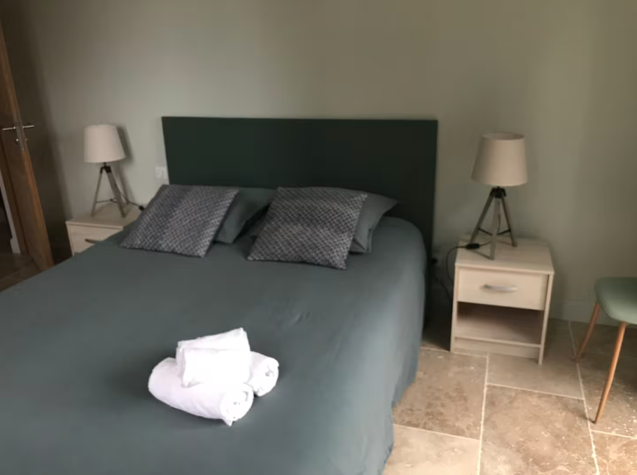 A bedroom with a bed , two nightstands and two lamps.