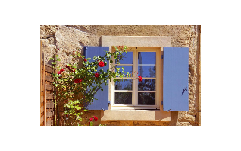 A window with blue shutters on a stone building