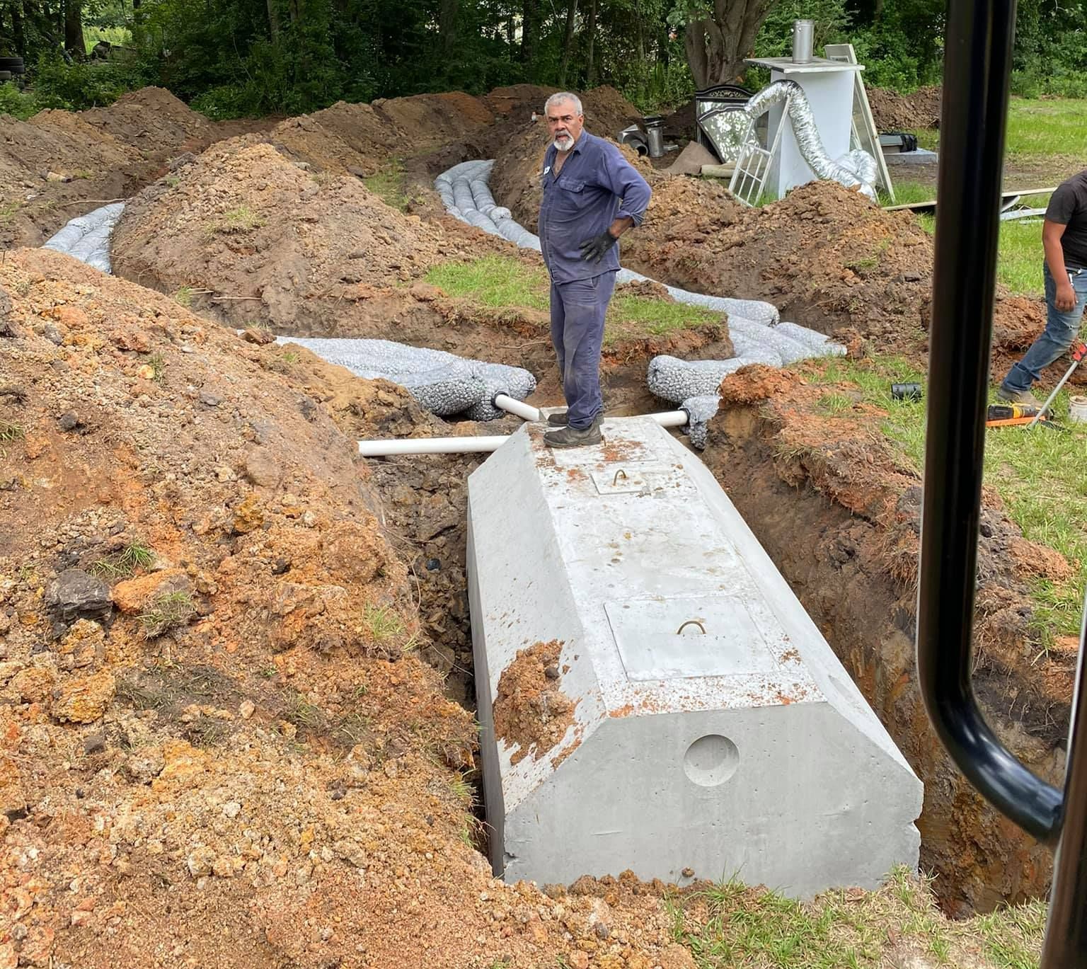 A man is standing on top of a concrete block in a dirt field.