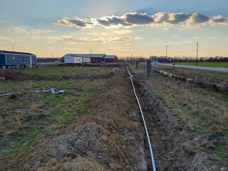 A pipe is being installed in the dirt in a field.
