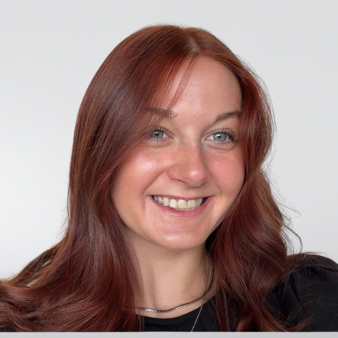 Smiling woman with long auburn hair against a plain white background