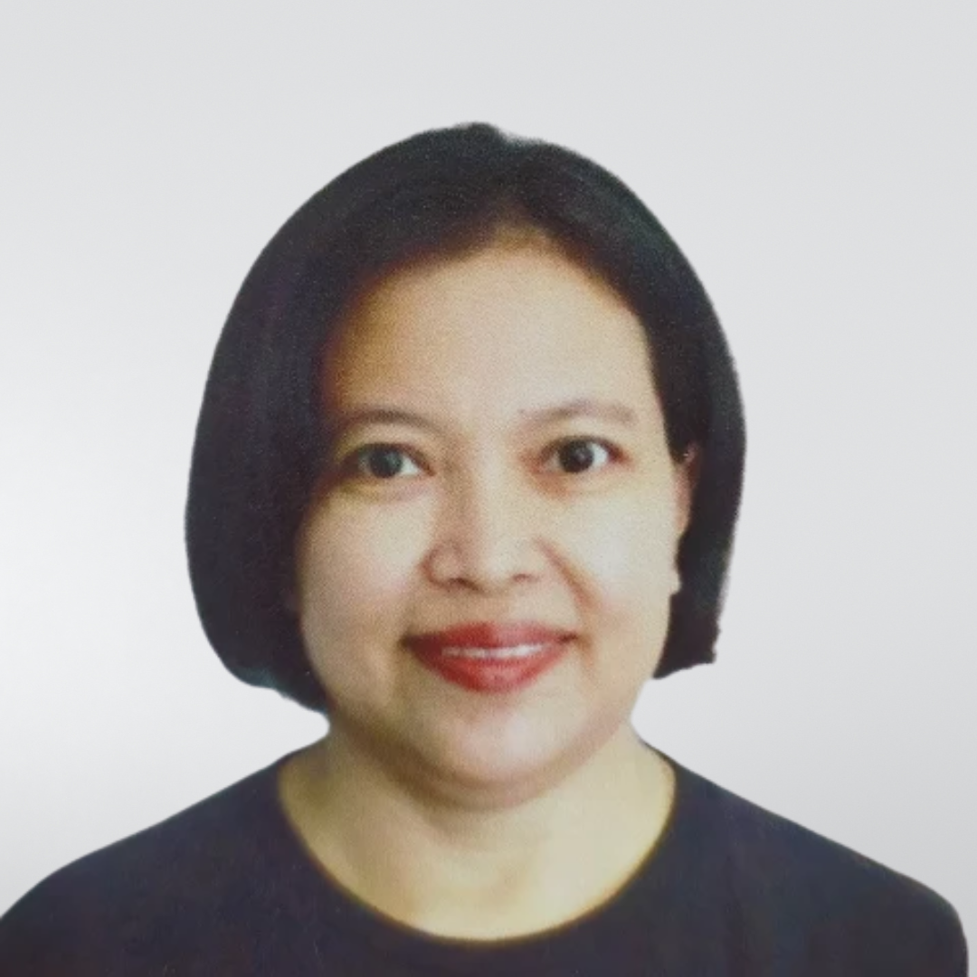 A person with a dark bob haircut and dark shirt, smiling against a plain, light gray background.