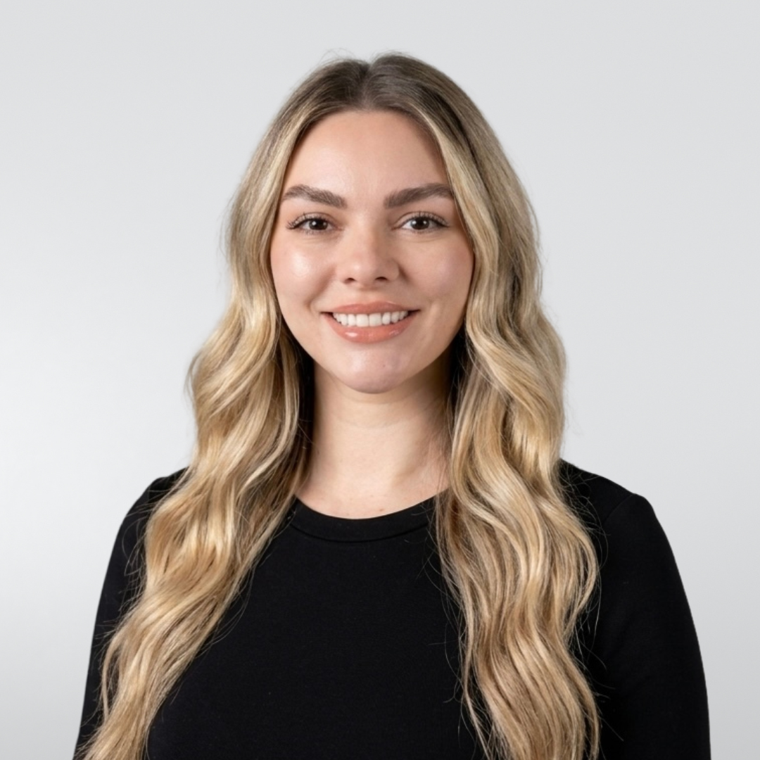 Smiling blonde woman in a black top against a light gray background