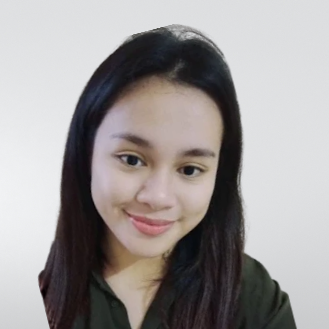 A smiling person with long dark hair, wearing a dark green shirt against a plain, light grey background.