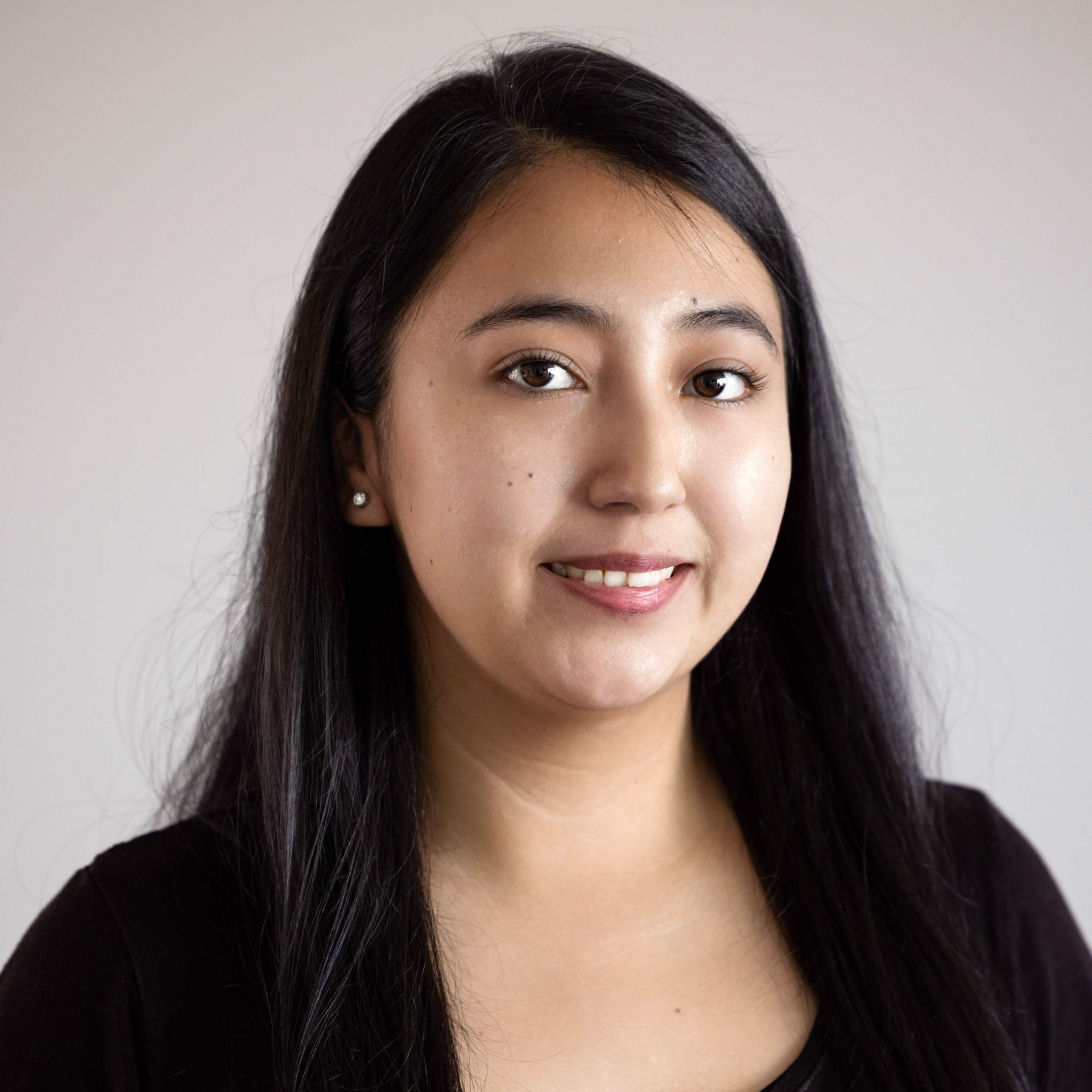 A woman with long black hair is smiling for the camera.
