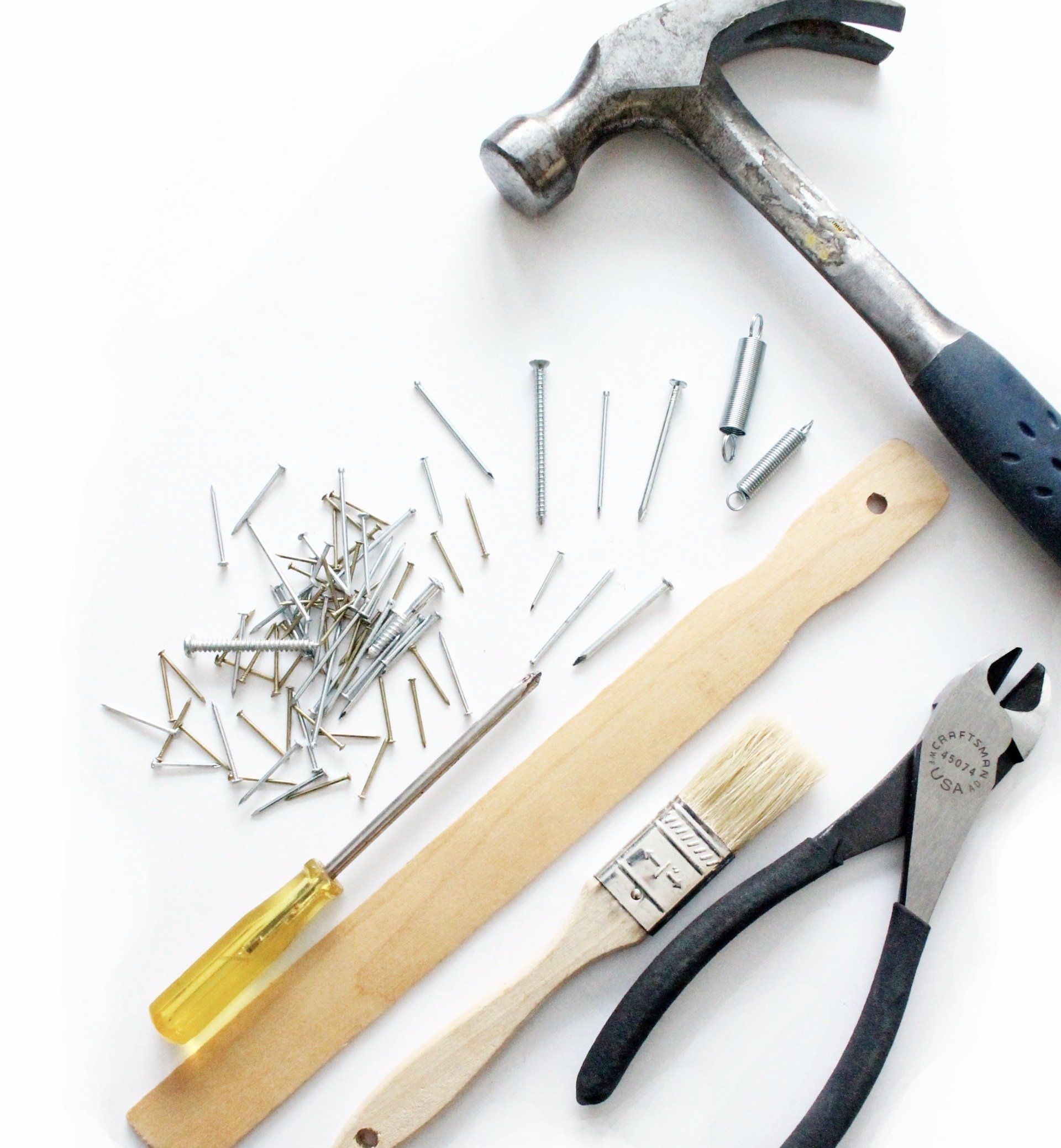 A hammer is surrounded by tools including a screwdriver and pliers