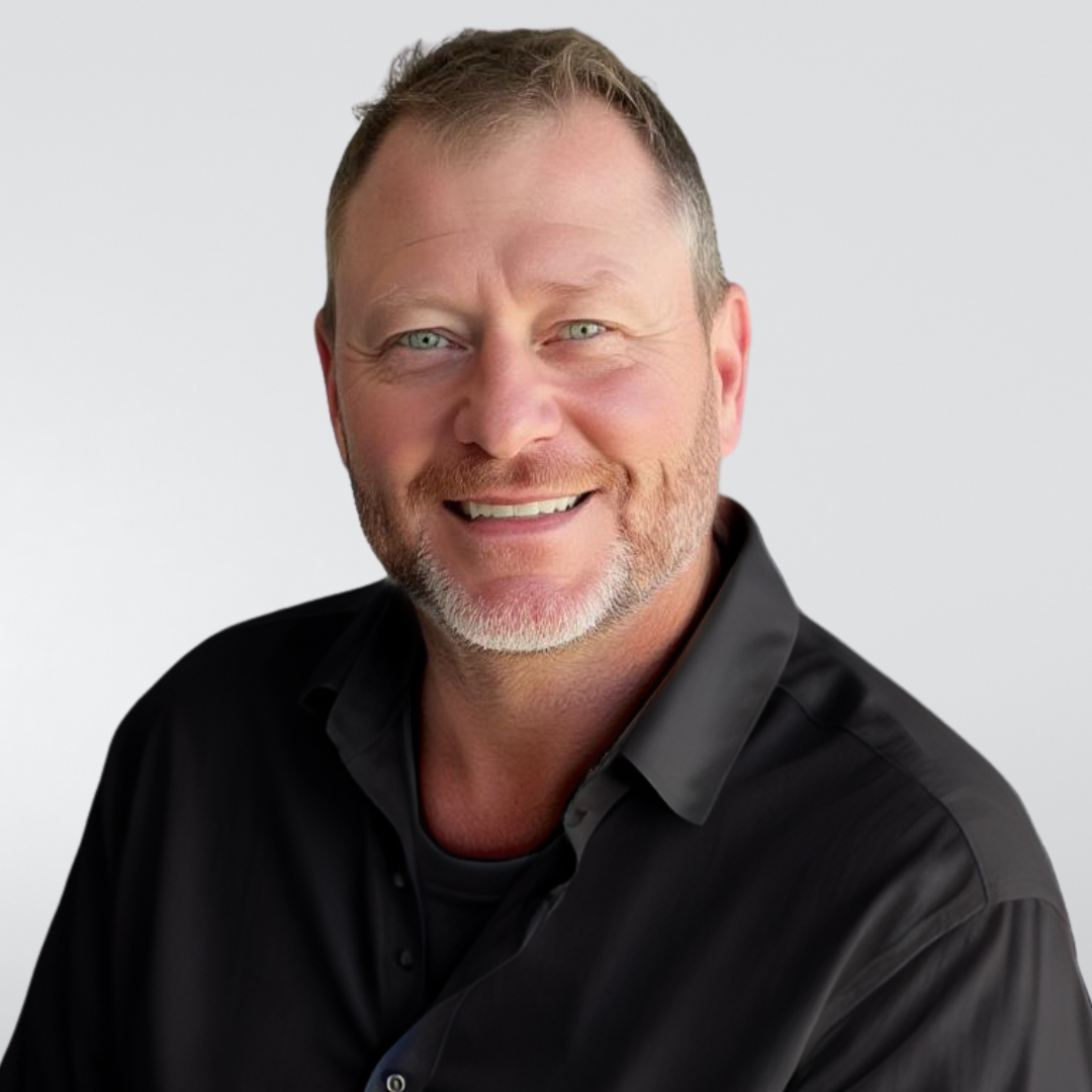 Man smiling, wearing a cream button-down shirt, neutral background.