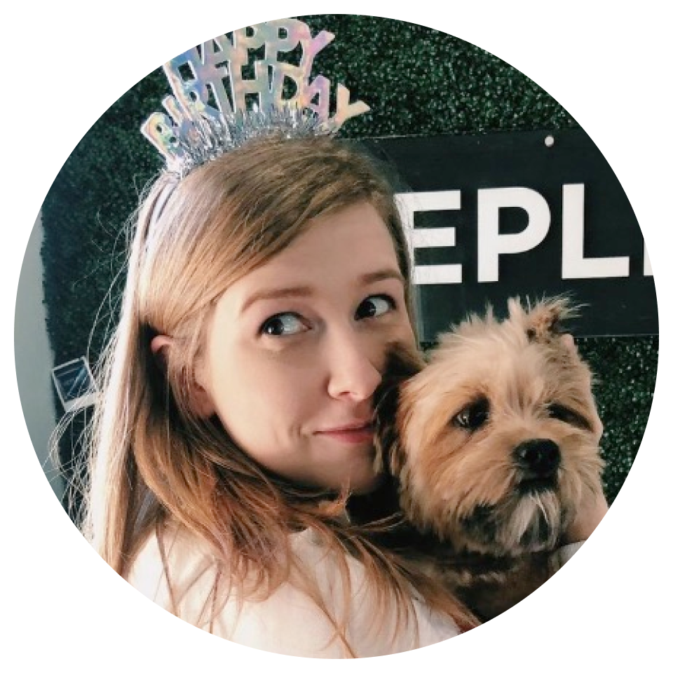 A woman wearing a happy birthday headband holds a small brown dog