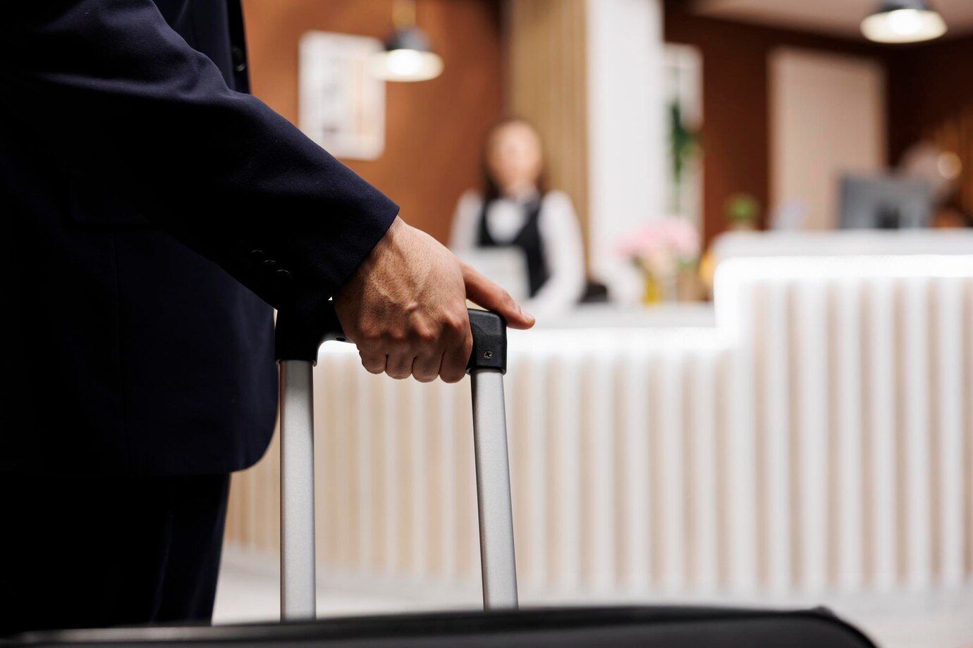 A man in a suit is holding a suitcase in a hotel lobby.