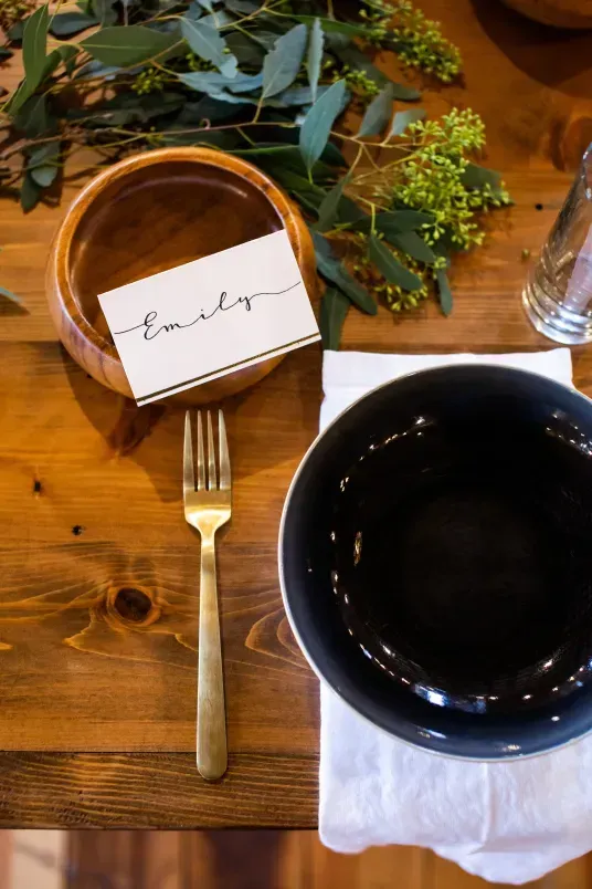 A place setting with a wooden bowl, name card for