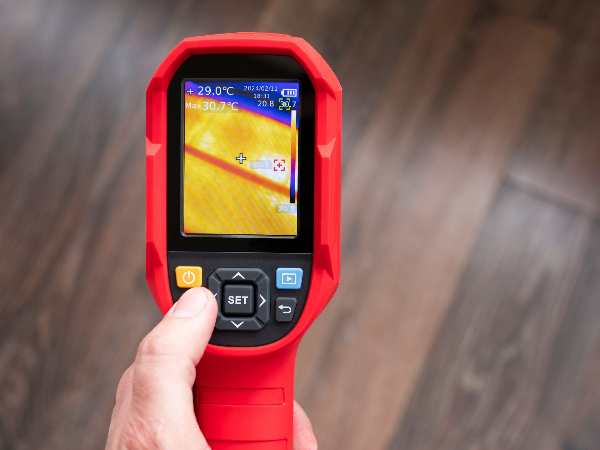 Technician using a thermal imaging camera to detect an underground water leak.