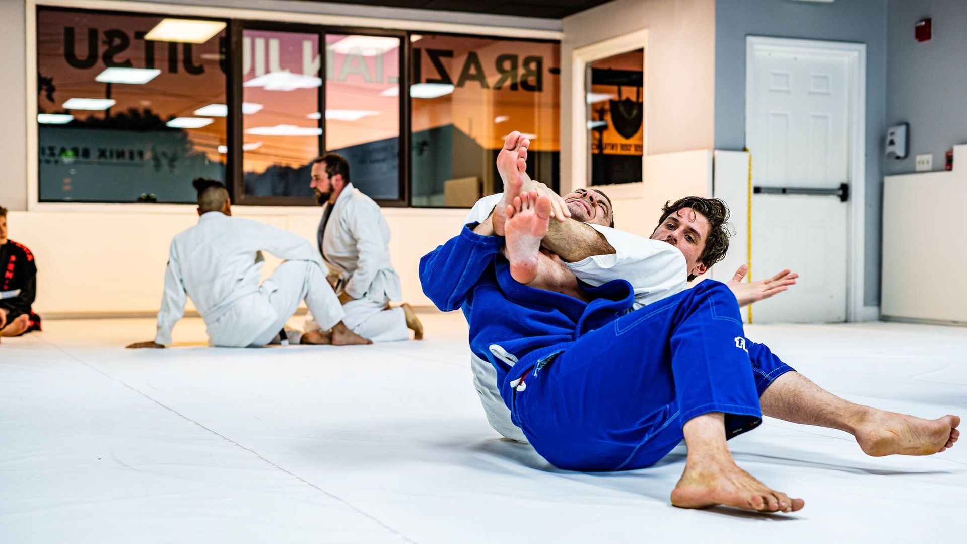 A group of men are practicing jiu jitsu in a gym.