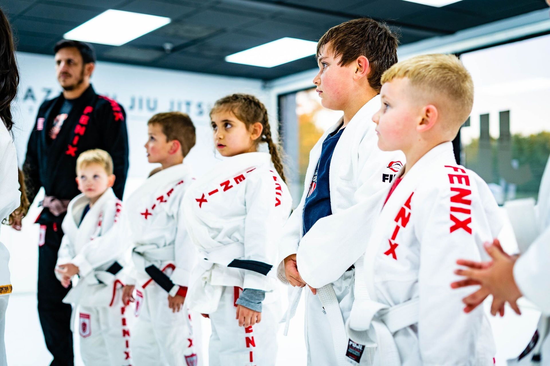 A group of children are standing in a row wearing white karate uniforms.