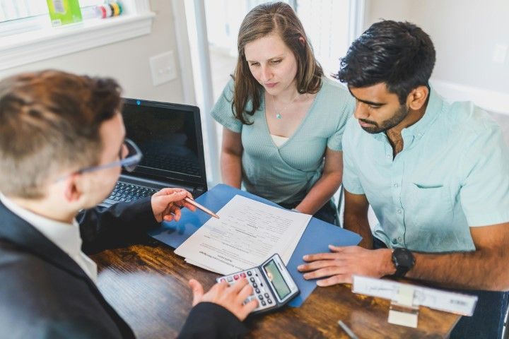 Real estate agent discusses PMI removal with couple at table with laptop
