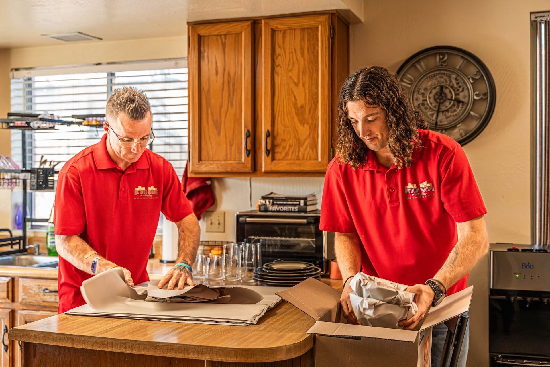 Two people in red shirts preparing food in a kitchen on a countertop