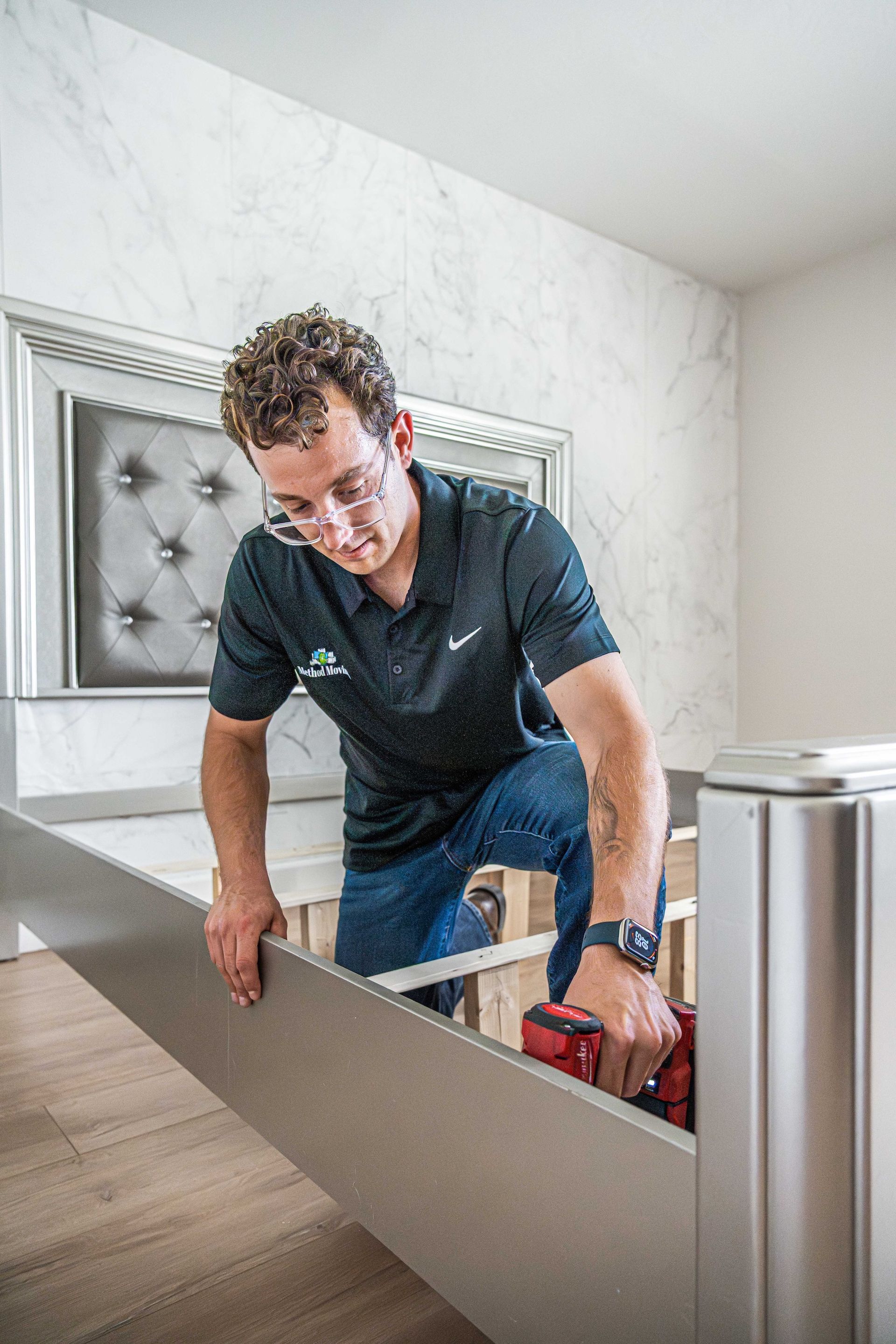 Person assembling a bed frame in a bright bedroom with tools nearby
