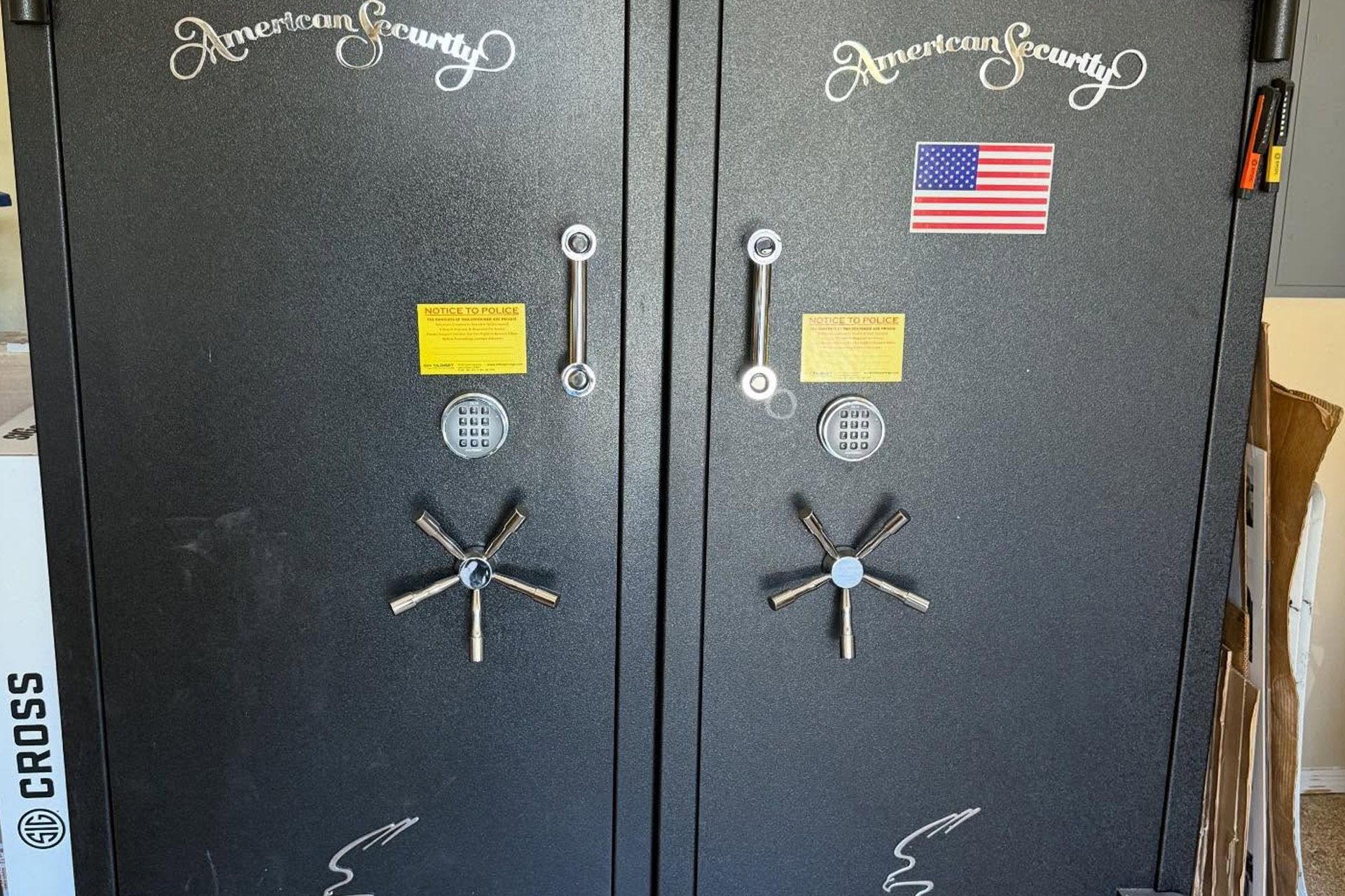 Two black gun safes with silver handles, combination dials, and warning labels; one has a U.S. flag sticker.