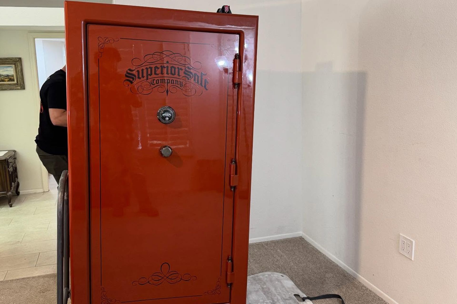Red safe cabinet in a room, with a person partially visible behind it.