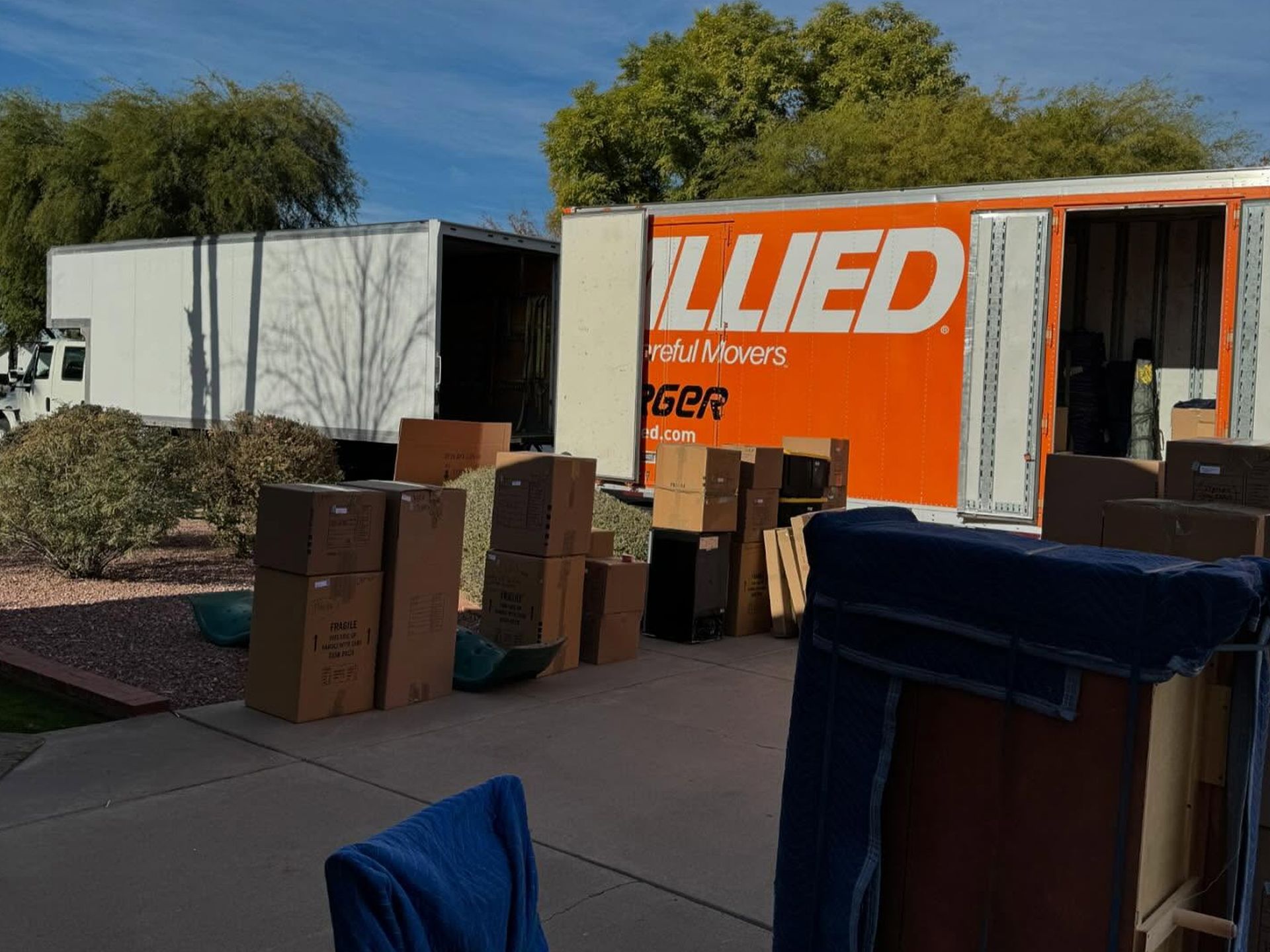 Moving boxes outside an Allied moving truck on a sunny driveway