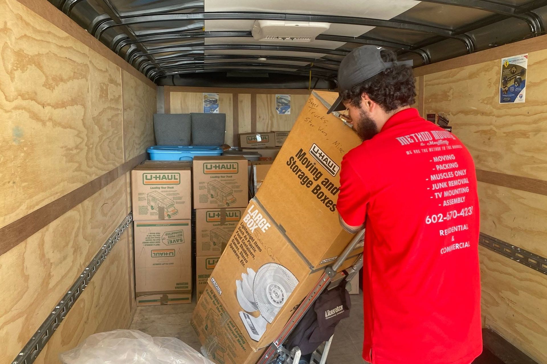 Mover in red shirt lifting a box inside a packed moving truck
