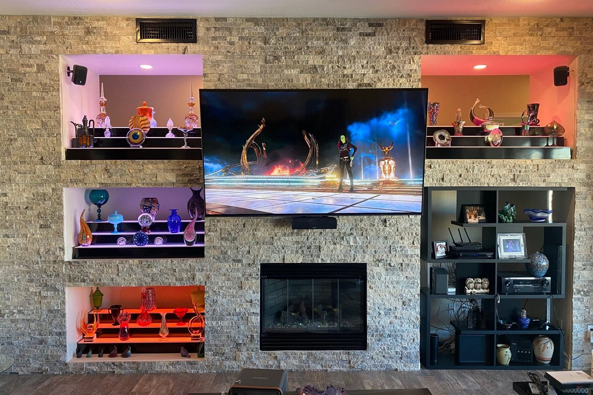 Stone fireplace wall with TV, built-in shelves, and colorful aquarium-themed decor
