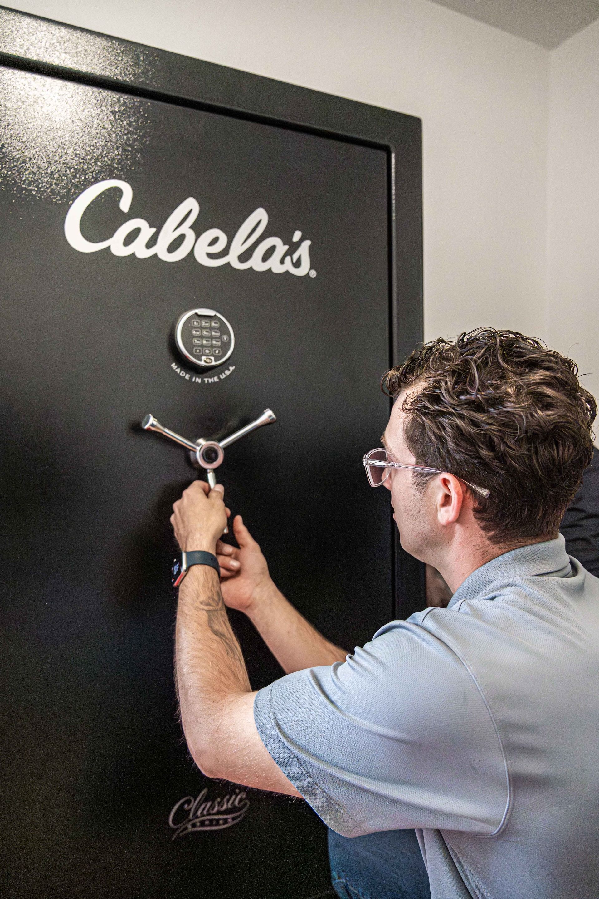 Man opening a Cabela’s gun safe with a combination dial and handle