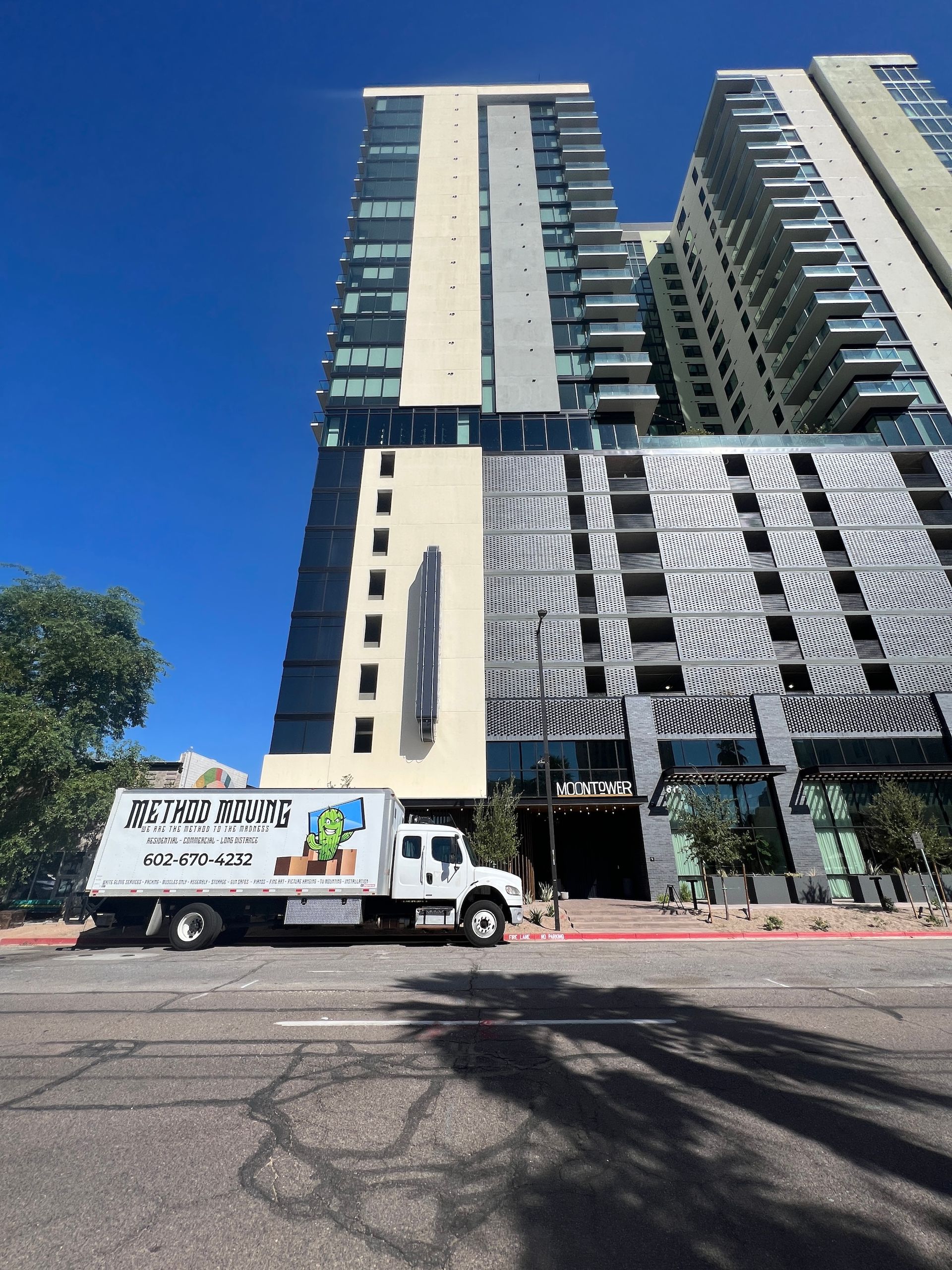 Delivery truck parked before tall modern apartment towers under a bright blue sky
