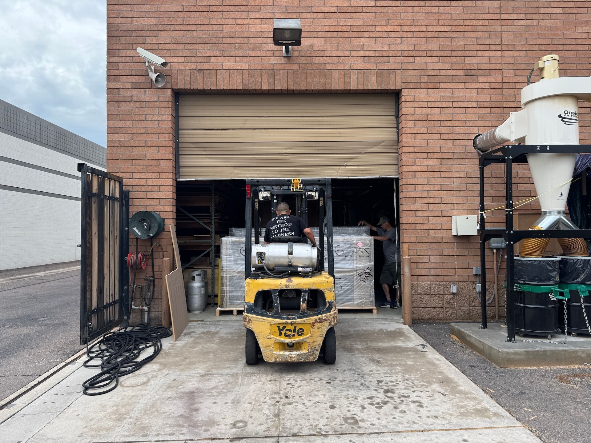 Yellow forklift at a warehouse loading bay, with a partially open garage door and industrial equipment nearby.