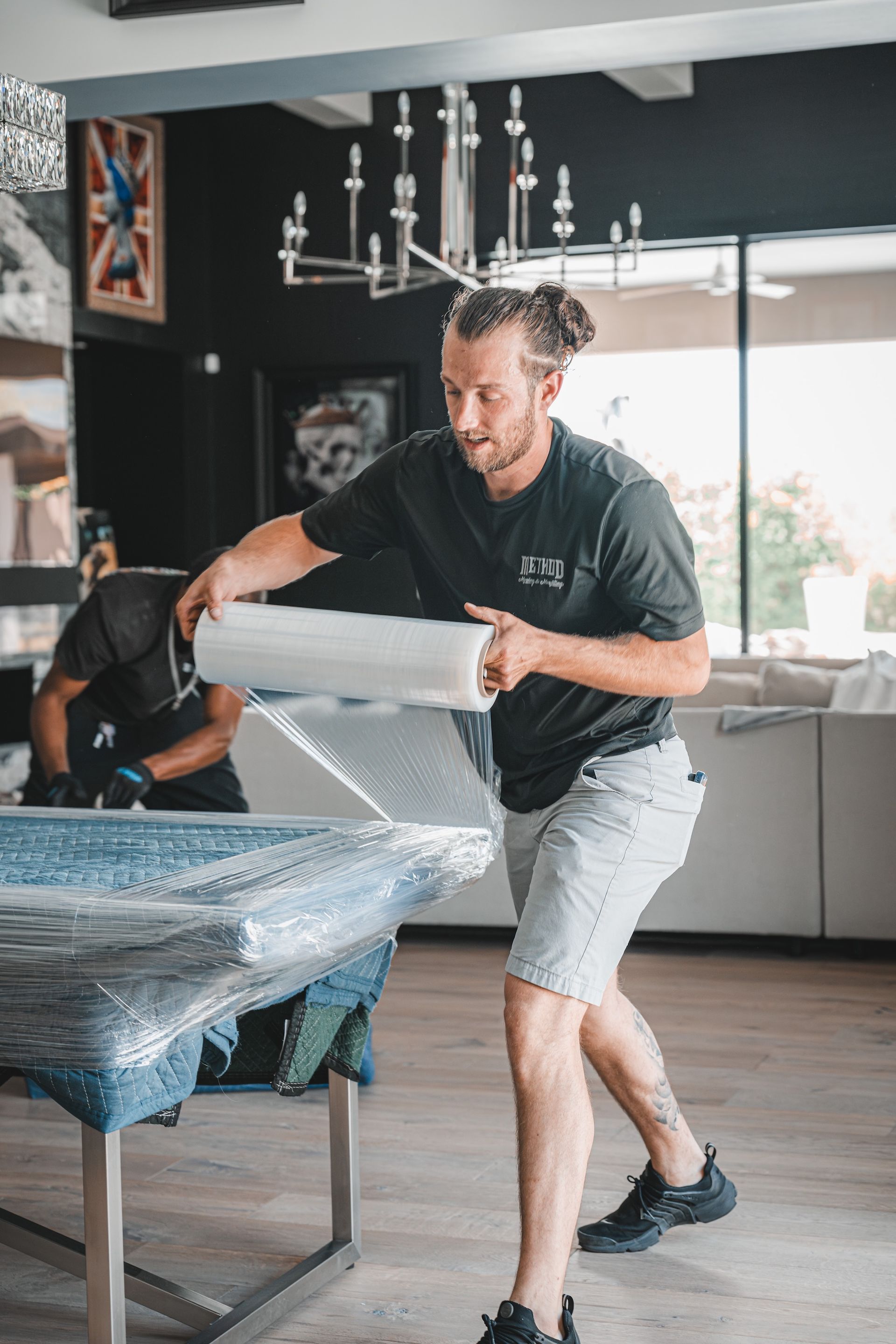 Man wrapping bubble wrap around a tabletop in a bright dining room