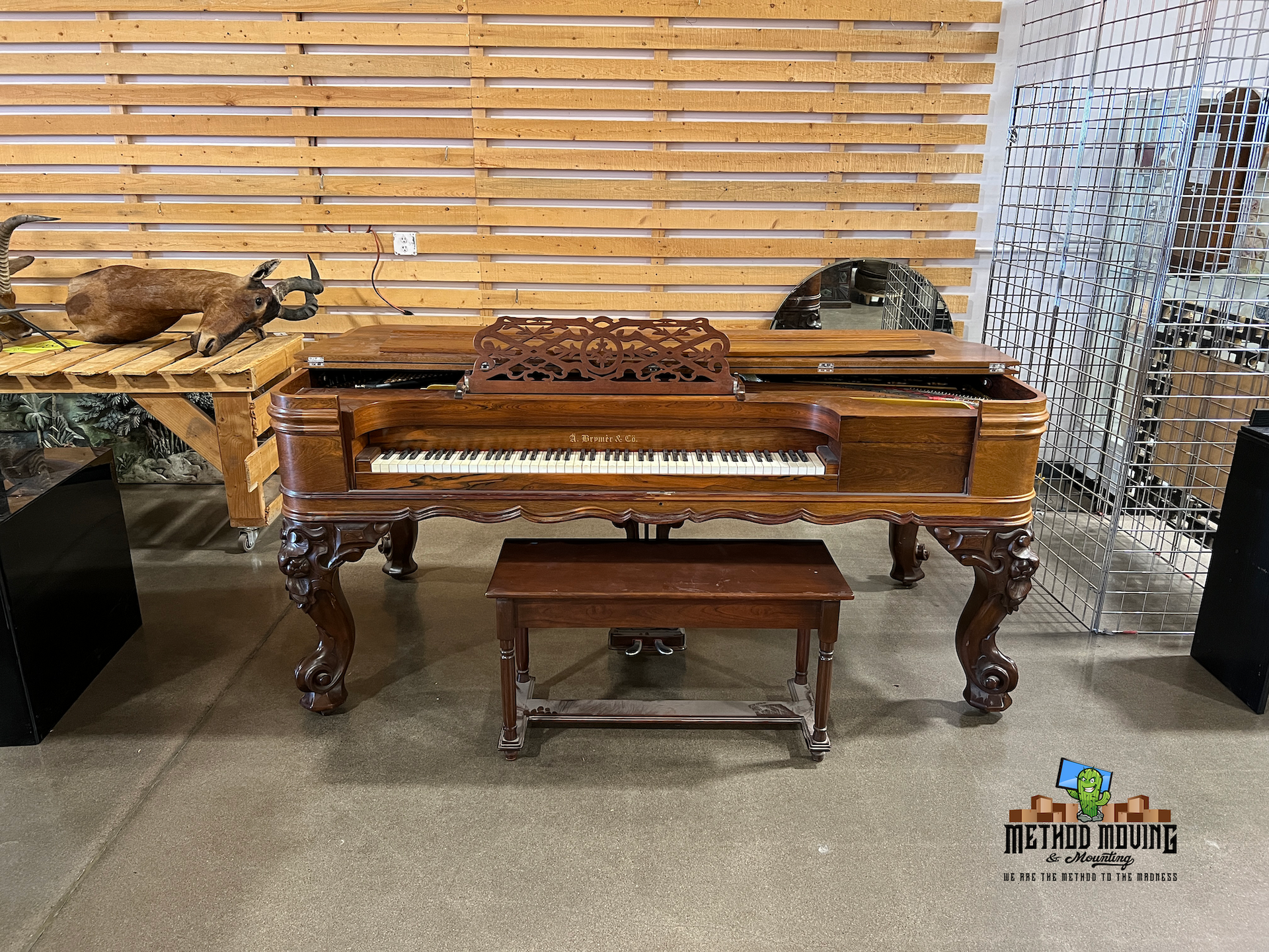 Wooden xylophone-like instrument on a table with benches, in a display area with a slatted wood backdrop
