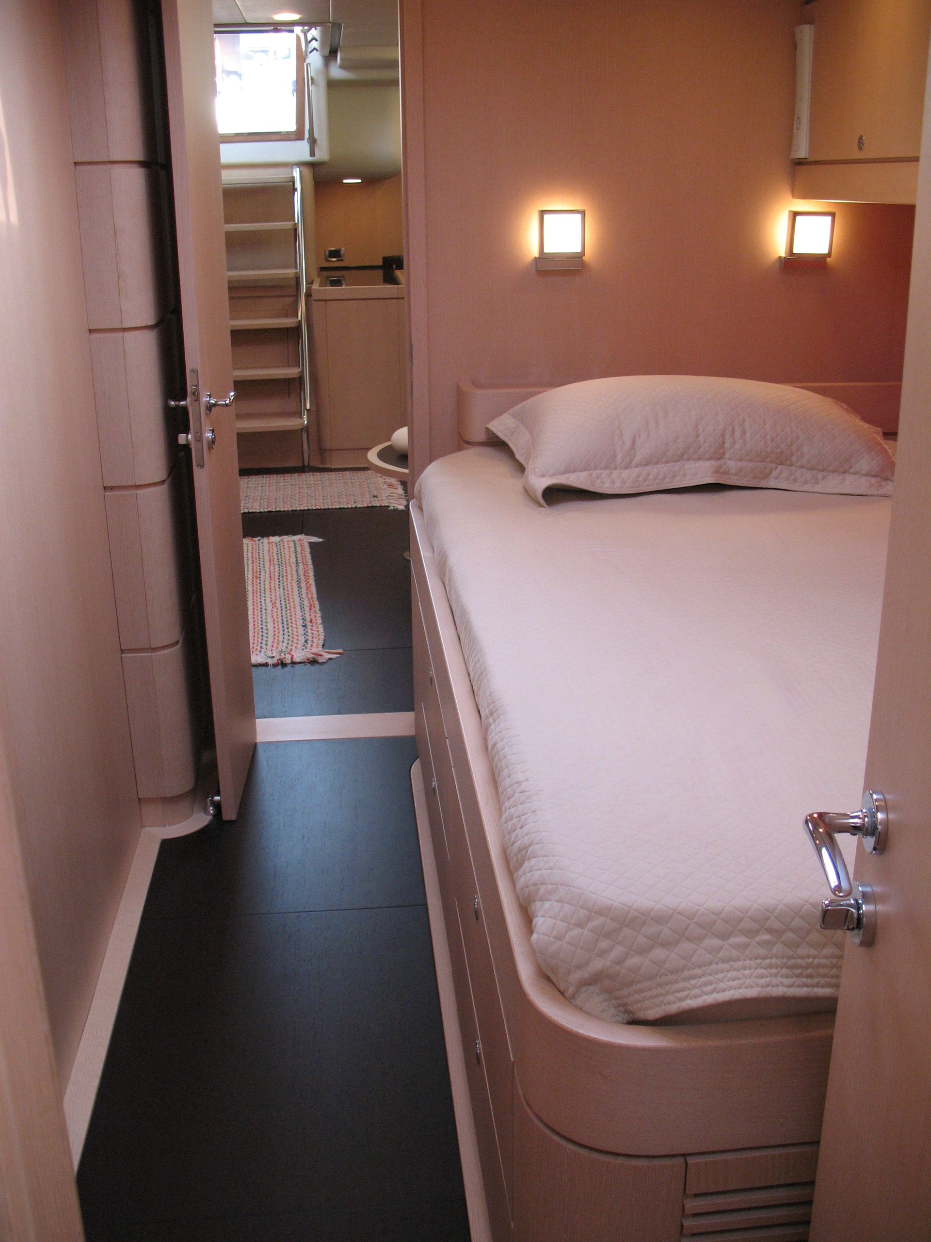 Una camera da letto di uno yatch con un letto e una scala sullo sfondo