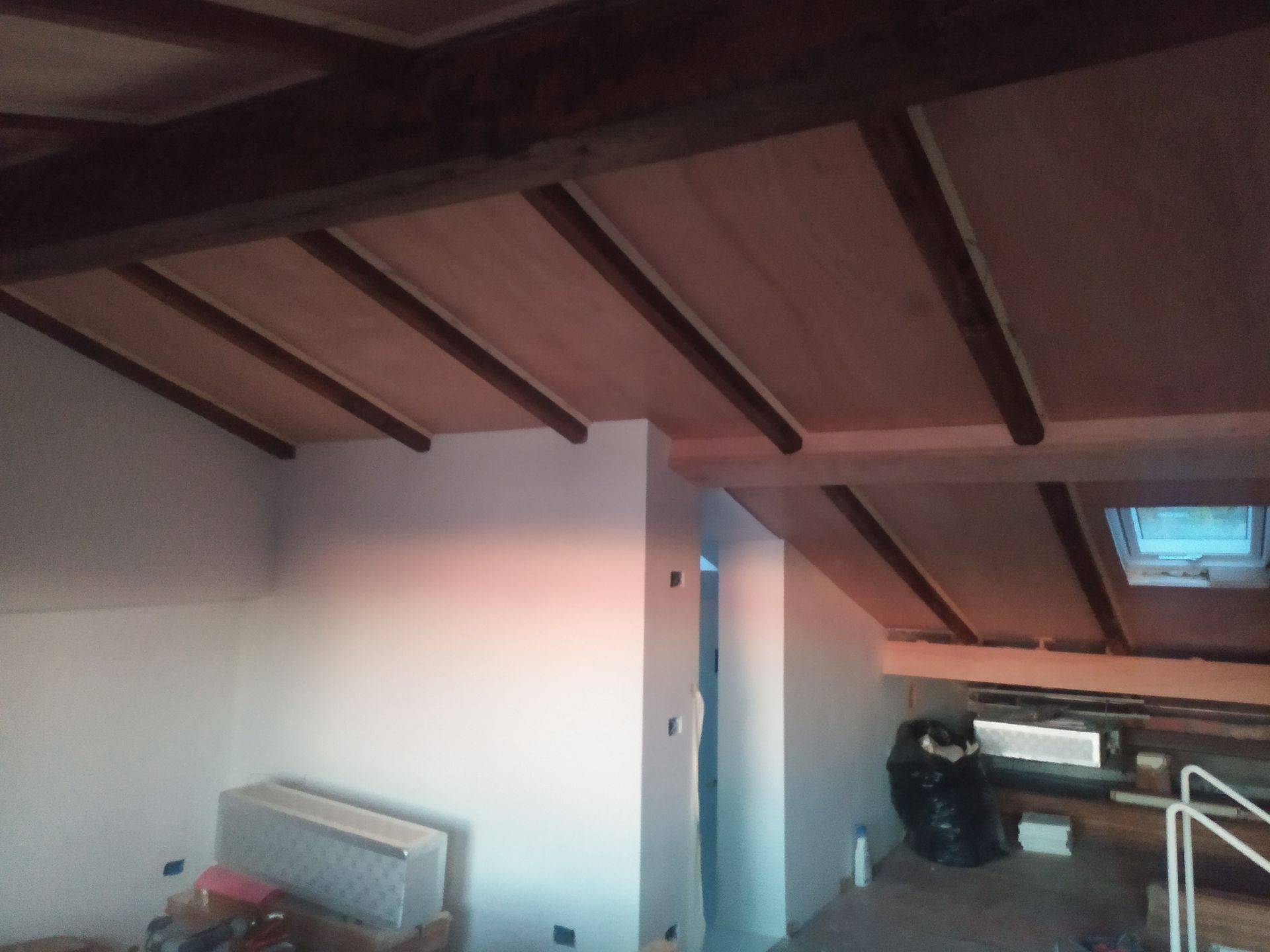 Una stanza con soffitto in legno e lucernario
